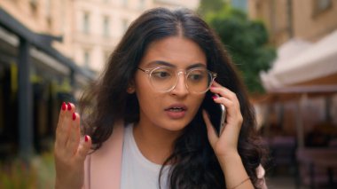 Kızgın, sinirli, Hintli, Arap, etnik kadın, iş kadını, yürüyen şehir kadını, bağır, cep telefonu görüşmelerini tartış.