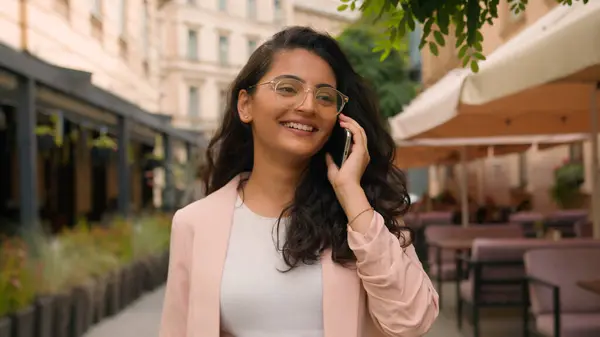 Laughing smiling woman Indian Arabian ethnic happy female girl businesswoman student talking mobile phone call telephone walking city street cafe. Discussion online connection outside travel outdoors