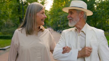 Mutlu, yaşlı, zarif, beyaz, yaşlı bir çift el ele tutuşup gülümseyen yaşlı kadın aşıklar şehir parkında keyifli sohbetlerle çıkıyorlar. Sağlık hizmetleri emeklilik ilişkisi