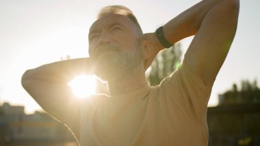 Kafkasyalı yaşlı sporcu sabah ısınma sporu alıştırması yapıyor. Emekli olmuş yaşlı stadyum şehri erkeklik gücü hareketi dışında rutin aerobik jimnastik vücut bakımı.