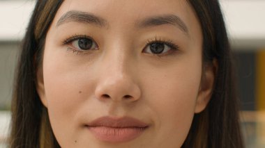 Yakından bakınca, 20 'li yaşlarda Asyalı genç bir kız Çinli güzel bir Japon kadın yüz derisi mükemmel doğal güzellik makyajı bayan fotoğrafçı Asyalı iş kadını kameraya bakıyor.