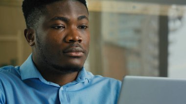 African American man businessman adult ethnic entrepreneur sit at office desk indoors male employee 30s manager working with computer laptop search data on internet studying online business commerce