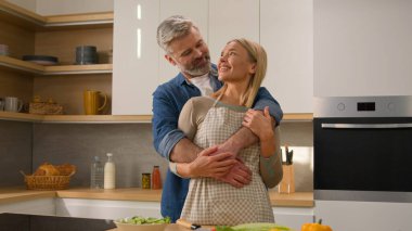 Mutlu aile fertlerini kaygısızca seven yetişkinler orta yaşlı eşler olgun kadınlar birbirlerine gülümseyen, sevgi dolu ev sahipleri mutfak aşçılarının ev portresine sarılıyorlar.