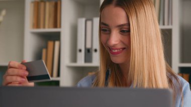 Beyaz, mutlu, güler yüzlü bir kadın internetten sipariş servisi satın alıyor. Laptop ve kredi kartıyla alışveriş yapıyor. İnternet bankası uygulaması ile bilgisayar bankacısı kız müşteri satın alıyor.