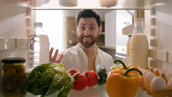 Point of view POV inside refrigerator happy excited hungry Caucasian man open fridge full of healthy vegetables many products meal take sniffing fresh tomato good smell food delivery service cooking