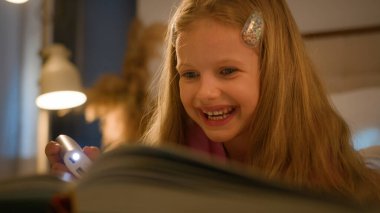 Mutlu gülümseyen beyaz kız, akşamları elinde fenerle kitap okuyor. Yatakta dinleniyor, tatlı bir çocukta öğreniyor. Masal masallarından zevk alıyor.