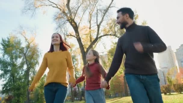 ハッピーコーカサスの人々 都市公園森林自然秋の晴れた天気の良い天気の家族のお父さんと娘は笑顔の散歩 手を握る 母親のお父さんは楽しんでいる実行している腕の子供ガール — ストック動画