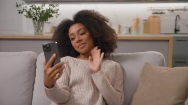Mutlu gülümseyen Afrikalı Amerikalı kadın cep telefonuyla konuşuyor. Akıllı telefon çevrimiçi. Sanal kız, etnik kızla buluşuyor.