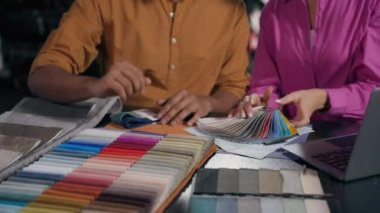 Tanımlanamayan kadın erkek moda tasarımcıları atölyeden tekstil almayı seçiyorlar. Seçilmiş malzemeler, kırpılmış malzemeler. Elleri kumaş örneği, renk tonu, palet rengi kumaş tasarımı ile eşleşiyor.