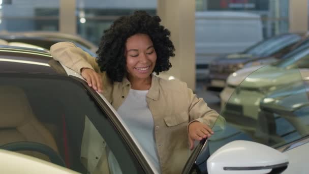 快乐顾客客户非洲裔美国女商人买新车享受奢侈购物在汽车经销店女业主买租车现代电动汽车看相机笑 — 图库视频影像