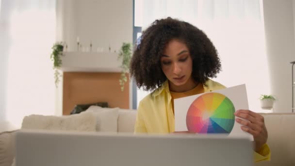 アフリカ系アメリカ人女性女性ホームインテリアデザイナー オンラインチャットビデオ通話 クライアントとのノートパソコンショーペーパースケッチ 家のリフォームグラデーション色の創造的なアイデアのための色の選択 — ストック動画