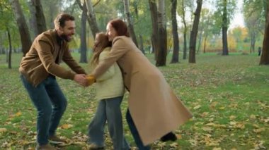 Mutlu aile neşe dolu kahkahalar atan samimi anne-baba rolü yapan, el ele tutuşan, çocuk kız çocuk oyun oynayan, hafta sonu aktif oyun oynayan şehir parkı, anne-baba kucaklaşan baba gülüşü.