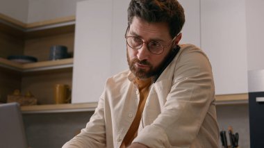 Ev telefonuyla konuşan, birden fazla işi olan beyaz tenli bir adam karantinada serbest çalışan bir iş adamı. Erkek müşteri mutfakta bilgisayar uygulaması ve akıllı telefonla yemek siparişi veriyor.