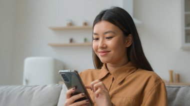 Asyalı Koreli iş kadını kadın serbest çalışan mutfakta çalışıyor. İyi haberler okuyor, gülümsüyor cep telefonu kullanıyor, internetten sipariş dağıtımı yapıyor, cep telefonu sohbeti yapıyor.