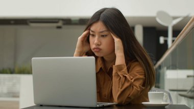 Asyalı üzgün kadın yorgun, bitap düşmüş Koreli Japon iş kadını laptopçu işinde endişeli kız, bilgisayardaki kötü haber üzerine stres bozukluğu yaşıyor.
