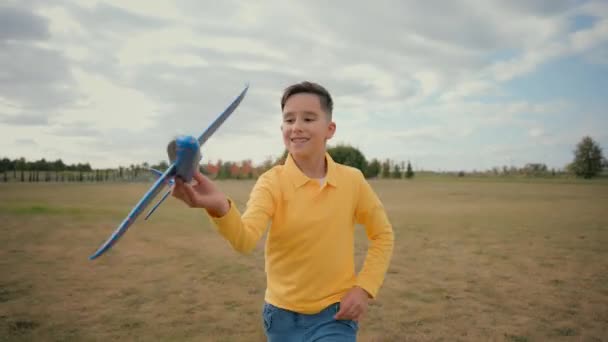エキサイティングな幸せなコーカサス少年の男の子は 野外の田園地帯公園の外で将来の宇宙飛行士を夢見ているおもちゃの飛行機を再生するランニングを実行します 子供は飛行機のフリーダムファンタジーの願望をプレイ — ストック動画