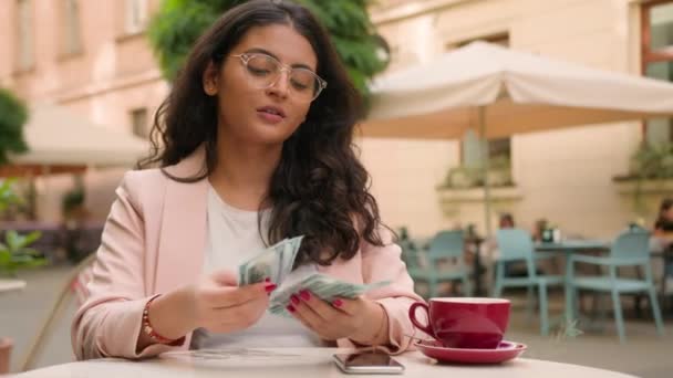 裕福なクライアントを閉じる インドのアラビアのエスニック女性幸せなビジネスウーマン女性は 都市カフェの外でお金を数えるドル紙幣を保持しています 金融会計 — ストック動画
