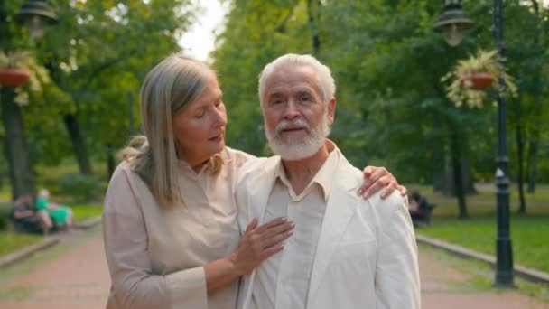 上了年纪的白种人相亲相爱的夫妇上了年纪的祖父母和家人相亲的妻子拥抱在公园外散步 退休金领取者男人女人愉快的谈话 说着话漫步在小巷里 — 图库视频影像