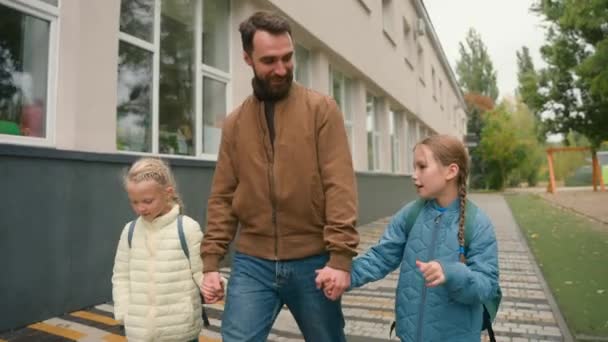 爸爸和两个女儿 小女孩 女学生 走在街头 与家人牵着手聊天 分享消息 快乐的一起加入团结关系对话 谈论为人父母的安全照顾孩子 — 图库视频影像