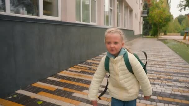 欧洲小女孩背着背包在学校外的人行道上跑来跑去的小女孩小学周末教育小学生步行城市秋天快乐的小女孩跑得很活跃 — 图库视频影像