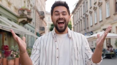 Genç beyaz Avrupalı adam gülümseyen zafer işaretleriyle seviniyor. İyi şanslar bağırarak evet hurray şehir sokağı. Keyif alan mutlu adam heyecanlanan duygusal erkek şaşkına döndü.
