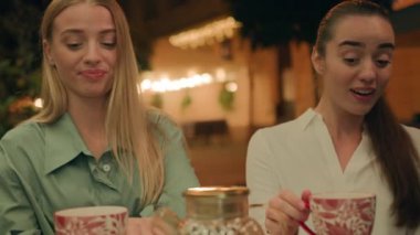 İki bayan arkadaş birlikte kafeterya şehrinin dışında gece vakti şaşırmış kadınların dedikodu muhabbetini tartışıp, suratını ekşitmeyi, gülmeyi, sıcak çay servisi yorumlarını eleştirmeyi kınıyorlar.