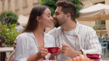 Mutlu genç çift erkek arkadaş, beyaz erkek kız arkadaş gülümsüyor, kahve içiyor, balayına sarılıyor, sevgi dolu aşk ilişkisi ile çıkıyor.