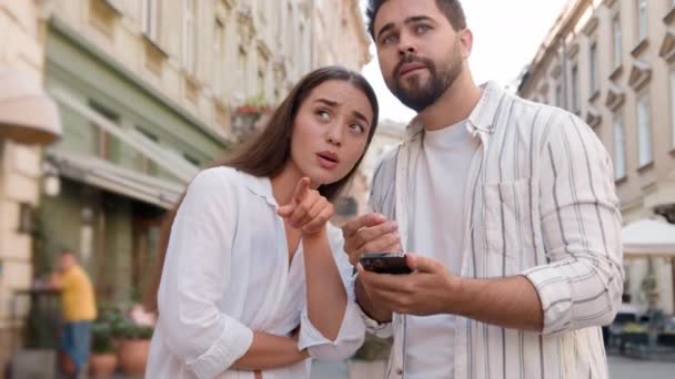 携帯電話のスマートフォンインターネットを使用してカップルの白人男性女性は 場所の観光ツアーGpsナビゲーションアプリの街の外側に位置をマップします 混乱した男性の女性のアトラクションの旅の方向都市 — ストック動画