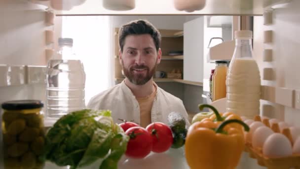冷蔵庫内からの眺めのポイント Povコーカサス人の男家主の家主の開いた冷蔵庫のドアのキッチン 食品笑顔を見つける赤いトマトを調理健康な菜食主義者 — ストック動画