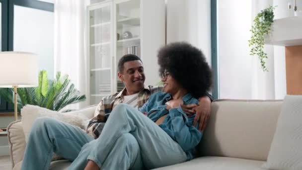 在家里的沙发上 一个男的和一个女的坐在沙发上 一起讨论家庭事务计划 笑着和他的丈夫拥抱 和他的妻子好好交谈 — 图库视频影像
