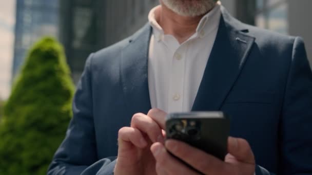 雇用主成熟した中年上級コーカサス起業家屋外の古いビジネスマンは スマートフォンアプリチャット携帯電話注文タクシーの側面を見ている都市の携帯電話の男性ビジネスマンを見ています — ストック動画