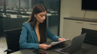 Kafkasyalı, iş kadını ofis çalışanı evraklarını dizüstü bilgisayarla ve kağıtlarla odaklamakla meşgul. İş kadını kadın yönetici bilgisayardaki verileri kontrol ediyor. Belge raporunda girişimci kız bilgi özgeçmişini analiz ediyor.