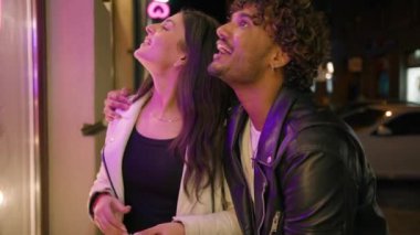 Akşam alışveriş torbalarıyla müşteriler dükkânın önünde durup vitrinlere bakıyorlar. Gülücükler saçan Hintli bir kadına gülümseyen adam hakkında konuşuyorlar.