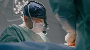 Koruyucu maske takan cerrah doktor doktor sağlık ekibi hasta laparoskopi cerrahi mikroskop ameliyatını ameliyathane hastane sağlık hizmetlerinde tıbbi aletlerle yapacak.