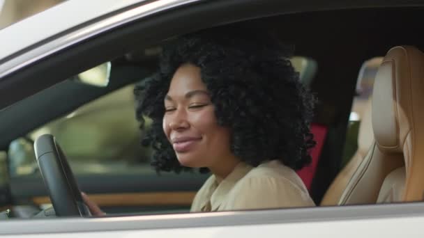 ハッピー笑顔のアフリカ系アメリカ人女性ビジネスマン 車内女性ドライバー ディーラーサロンで輸送を選択 満足したガールオーナー 新しい豪華な自動車購入の夢に触れる — ストック動画