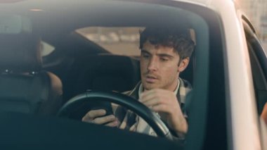 Stresli, üzgün, üzgün, beyaz bir adam otomobil şoförü, trafik sıkışıklığında bekliyor. Cep telefonu kullanıyor. Kötü haberler okuyor.