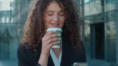 Tatmin olmuş Kafkasyalı kadın iş kadını kahve içip, internetten sosyal medyayı karıştırıyor kaygısız iş kadını yürüyüşü yapıyor cep telefonu akıllı telefon konuşmaları yapıyor.
