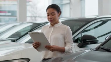 Afro-Amerikalı etnik kadın satış danışmanı araba satıcısı galeride otomobil seçmeye yardım ediyor. Gülümseyen mutlu kız galeride profesyonel satış müdürüne bakıyor.