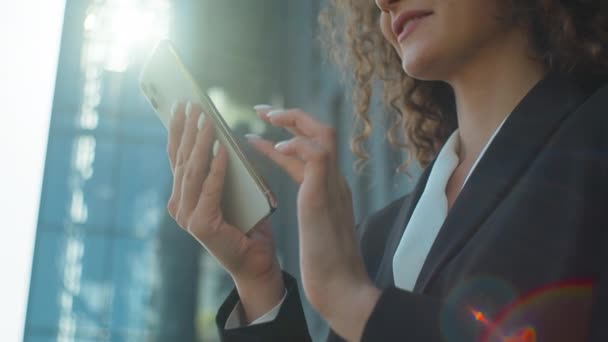 在城市里用智能手机紧握着女性的手拍摄微笑的商业女性手持手机连接发短信给社交媒体网上购物的女商人在户外晒太阳 — 图库视频影像