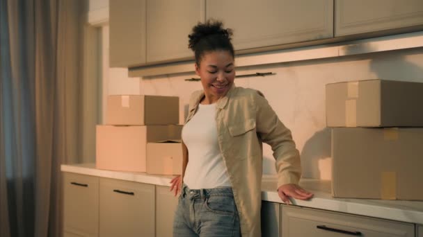幸せな喜びのアフリカ系アメリカ人女性 笑顔の少女 女性のホーム所有者 キッチンで新しい家に移転するテナント パックされた段ボール箱 喜びの移動日帰り 自分のアパートのローンの住宅を購入する — ストック動画