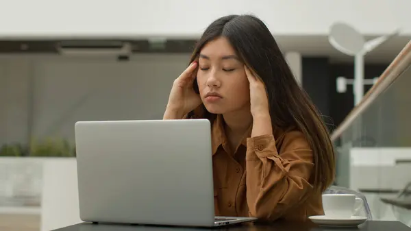 疲れ過ぎたアジア系中国人日本人女子学生オンライン勉強ノートパソコンでカフェ疲れビジネス女性は難しい意思決定が頭痛のマッサージ寺院痛みの頭に苦しむと思う — ストック写真