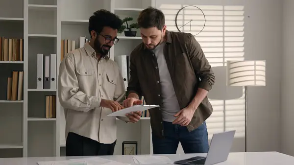 stock image Two multiethnic colleagues businessmen business coworkers at office discuss financial data project documents paperwork Caucasian Indian men prepare exam in library class corporate teamwork discussion