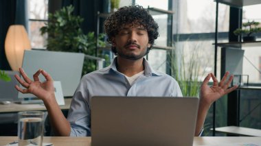 Sakin Arap adam Hintli işadamı ofis masasında meditasyon yapıyor. Zen meditasyonu. Rahatlamış erkek iş adamı CEO 'su.