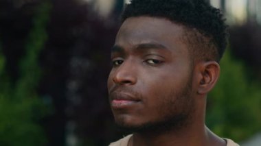 Yakın plan Afrika kökenli Amerikalı neşeli mutlu mutlu adam etnik melez adam milenyum erkek gülüşü dişlek dişçi şehrin dışında kameraman öğrencinin neşeli yüzüne bakıyor.
