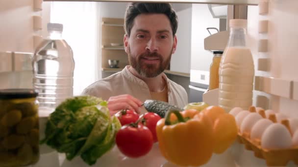 冷蔵庫内部のPovの視点 コーカサス人男性男性男性男性ホームナーシェフ 健康な新鮮な野菜でいっぱいのオープン冷蔵庫は キッチンフード配達でサラダを調理するためのトマトペッパーの卵を取ります — ストック動画