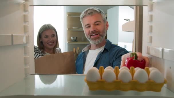 冷蔵庫の中からPovのポイント 中年カップルの大人の男と女性の夫と妻は 荷物の荷物の配達食品パッケージを解凍する冷蔵庫で健康的な野菜 — ストック動画