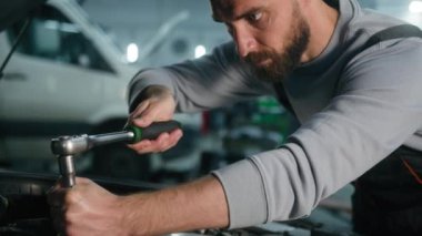 Beyaz tenli tamirci araba nakliyesi açık otomobil kaputu tamir motoru anahtarı tamir aracı tamircisi garajda yorgun işçi adam terini sildi.