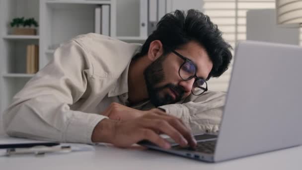疲れた睡眠疲れたアラビアのインドのビジネス男は欲求不満のビジネスマンの労働者従業員の悲しみの怠惰な男性はノートパソコンの退屈なコンピュータの仕事の昼寝のオフィスデスクで寝ています — ストック動画