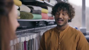 Kumaş dükkanında, çok ırklı Arap bir adam beyaz bir kadınla el sıkışıyor. Erkek moda tasarımcısı ve kadın müşteri el sıkışıyor. Kumaş dükkanında el sıkışma anlaşması satılıyor.