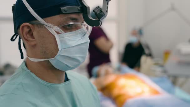 近视男医生内科医生神经外科外科医生穿制服的外科医生让病人做好手术准备 在医院诊所的手术室里开刀 — 图库视频影像